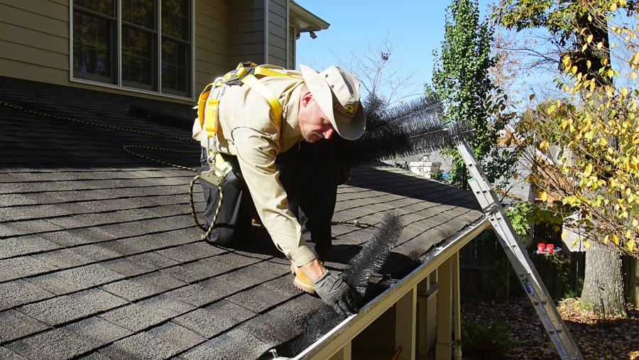 A technician installs a gutter protection system on the roof of a residential home.