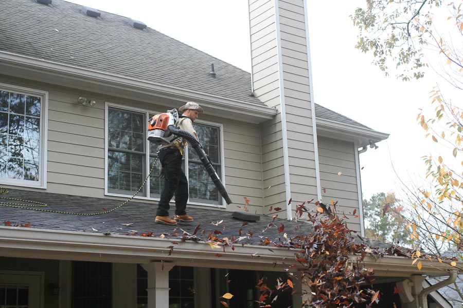 An Outback GutterVac technician blows leaves out of a client’s gutter.