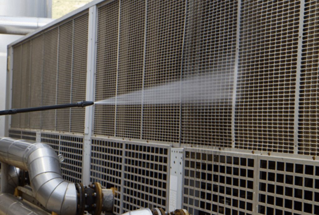 A power-washing hose cleans metal grating in an industrial building.