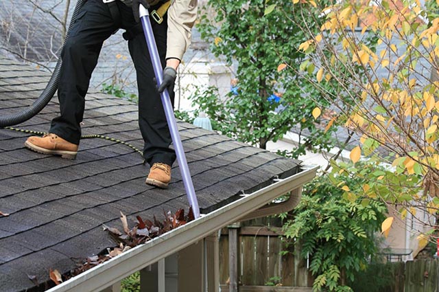 An Outback GutterVac technician uses the ThunderVac to clear leaves from a gutter.