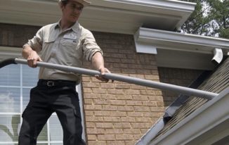 An Outback GutterVac technician vacuums leaves from a rooftop gutter.